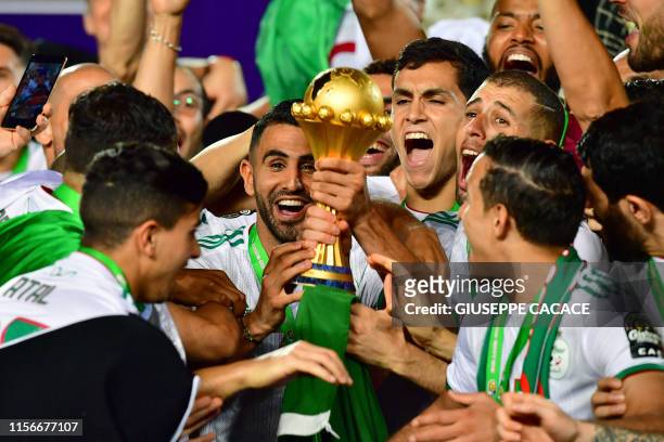 Algeria's forward Riyad Mahrez and his teammates celebrate with the trophy after winning the 2019 Africa Cup of Nations Final football match between...