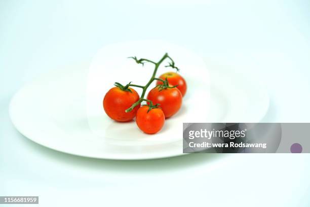 fresh red cherry tomato serve on white disk isolated over white background - cherry tomaten stock-fotos und bilder