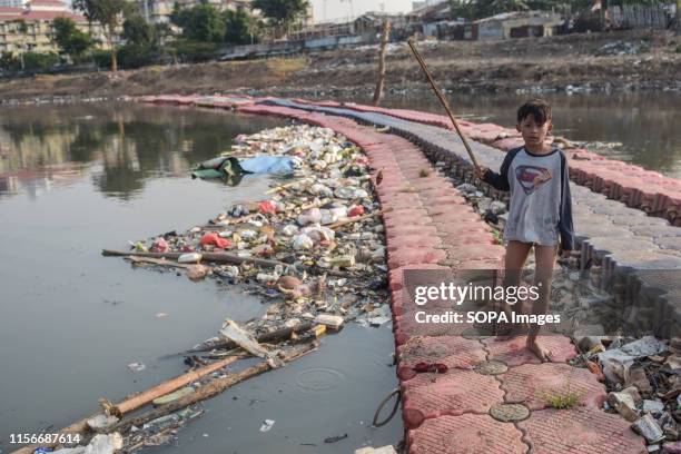 An Indonesian child from the slum area seen fishing at the river bank of the heavily-polluted Ciliwung River in Jakarta. Indonesia's Central...