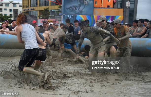 Tourists play in a mud pool during the 22th Boryeong Mud Festival at Daecheon beach in Boryeong on July 20, 2019. - The annual festival, which runs...