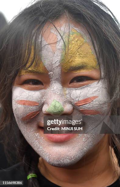 Woman's face is decorated with coloured mud during the 22th Boryeong Mud Festival at Daecheon beach in Boryeong on July 20, 2019. - The annual...