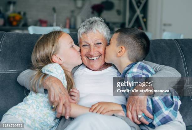 lovely kids kissing their grandmother - granddaughter stock pictures, royalty-free photos & images
