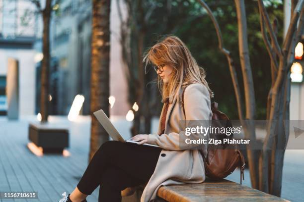 frau mit laptop auf einer bank - student laptop stock-fotos und bilder