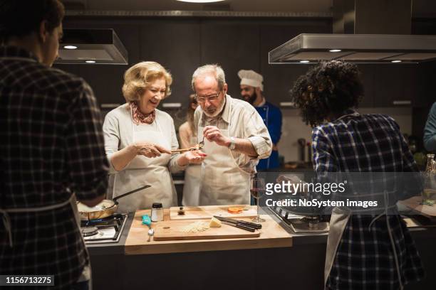 couples aînés préparant le repas - cours de cuisine photos et images de collection