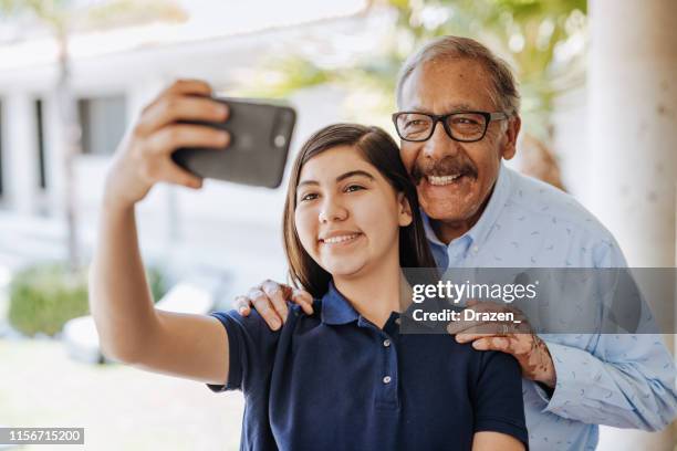 latino grandfather and teenage girl taking selfie - beautiful mexican girls stock pictures, royalty-free photos & images