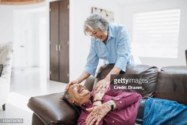 latina senior woman waking up her sleepy husband. - lazy husband stock pictures, royalty-free photos & images