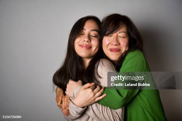 portrait of mother with mixed race teenage daughter - asian mother daughter stock-fotos und bilder