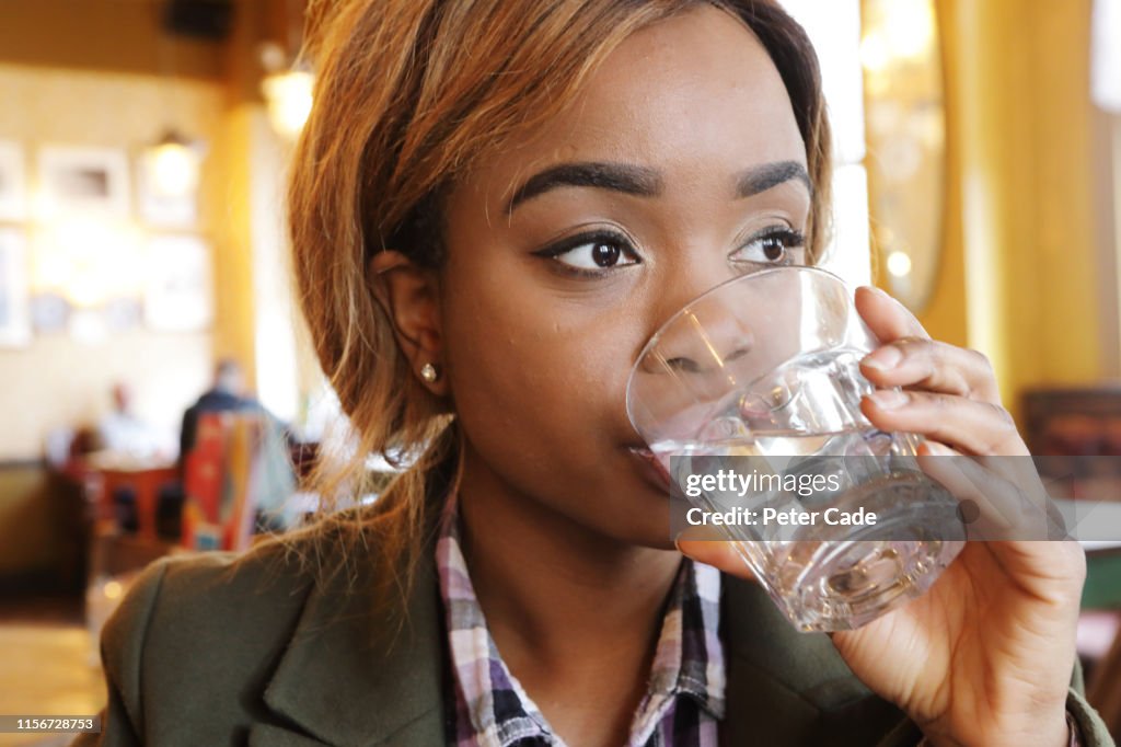 Young woman drinking water in cafe