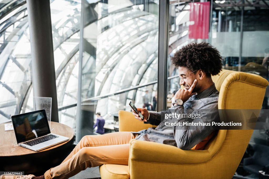 Business Owner Sitting In Chair Using Smartphone