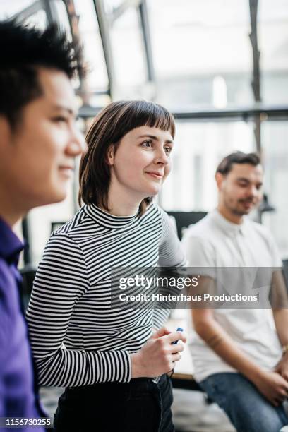 young woman listening intently during business meeting - grupo pequeno de pessoas imagens e fotografias de stock