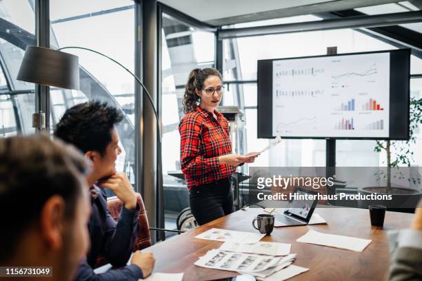 woman looking over charts and data during management meeting - strategia d'impresa foto e immagini stock