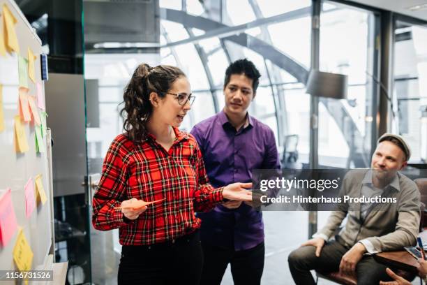 office manager using sticky notes on whiteboard during meeting - red dress shirt stock pictures, royalty-free photos & images