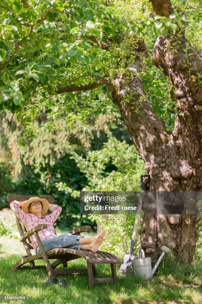 Gardening - senior woman in deck chair enjoy relaxing in garden outdoors