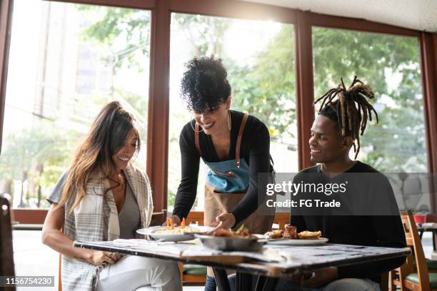 latin waitress serving food to a group of friends - serving size stock pictures, royalty-free photos & images