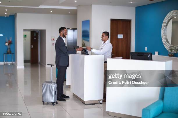 hotel receptionist assisting a guest. - hotel key stock pictures, royalty-free photos & images