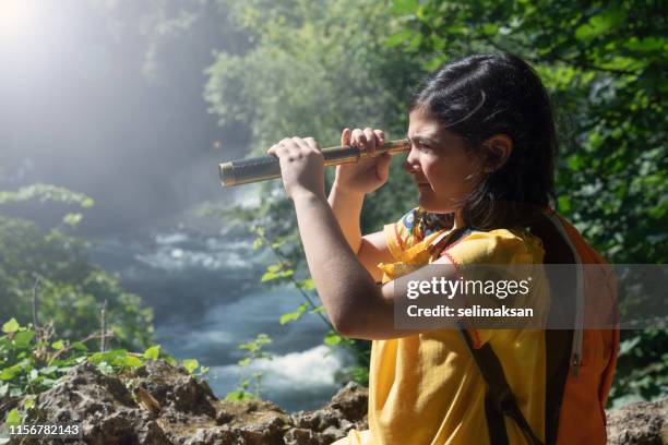 portrait of little girl looking through hand held telescope in nature - looking through telescope stock pictures, royalty-free photos & images
