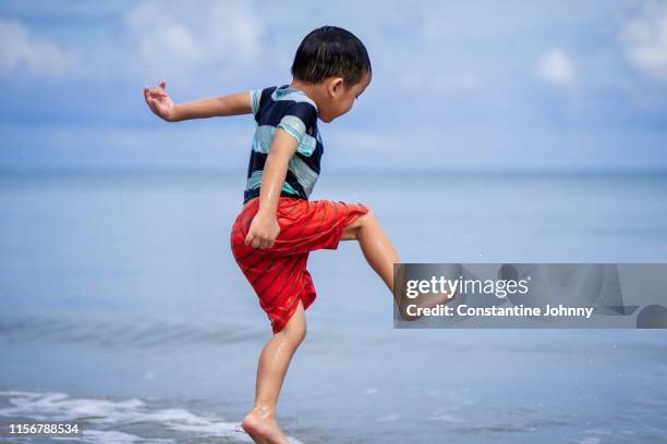 boy playfully jumping around on beach - kota kinabalu beach stock pictures, royalty-free photos & images