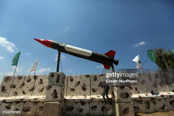 Palestinian; man ;stands ;near ;a monument ; a model ; Hamas; made; longer-range; M75 missile ; a military-style exercise ; a Hamas-run summer camp ;...