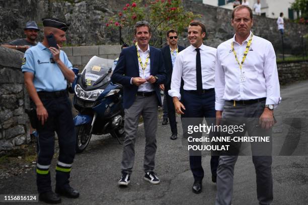 French President Emmanuel Macron walks with Tour de France director Christian Prudhomme on the route of the fourteenth stage of the 106th edition of...