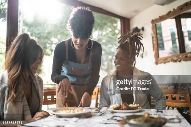waitress serving food to a group of friends - black chef stock pictures, royalty-free photos & images