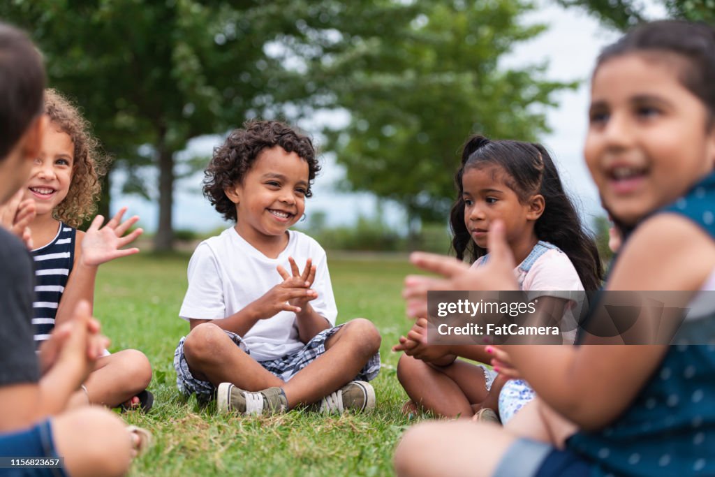 Een multi-etnische groep jonge kinderen klappen buiten