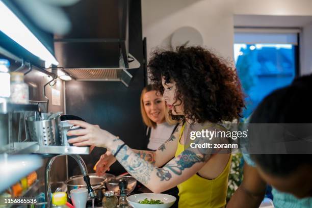 giovani coinquilini in cucina che preparano la cena - compagno di appartamento foto e immagini stock