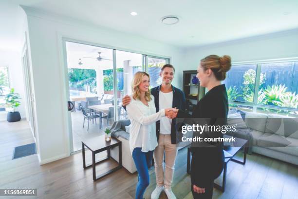 real estate agent with couple in luxury home. they are shaking hands. - estate agent stock pictures, royalty-free photos & images