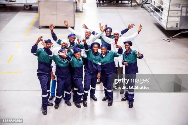 group of factory workers cheering togetherness - macacão preto imagens e fotografias de stock