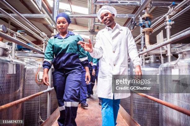 weibliche fabrikarbeiterin geht mit ihrem vorgesetzten in einer fabrik - food safety stock-fotos und bilder