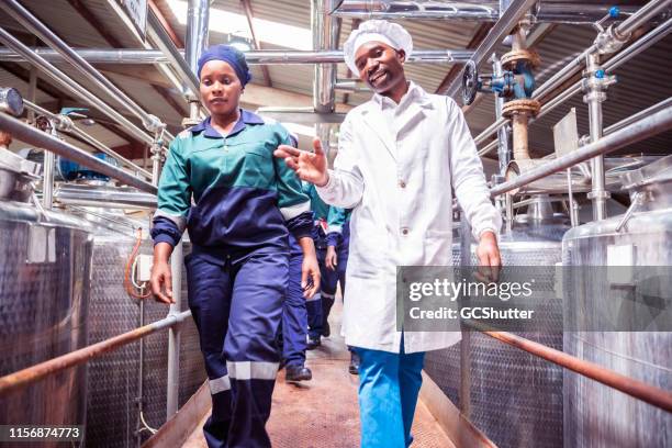 female factory worker walking with her supervisor at a factory - dairy factory stock pictures, royalty-free photos & images