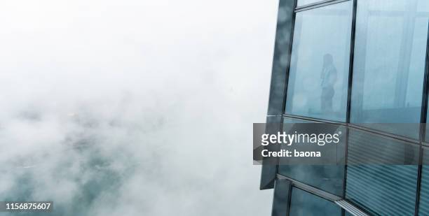 geschäftsmann steht in einem hochhaus mit blick über die stadt - luftverschmutzung stock-fotos und bilder