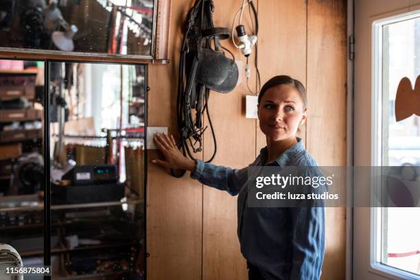 young female entrepreneur working at her small workshop business - turning on light switch stock pictures, royalty-free photos & images