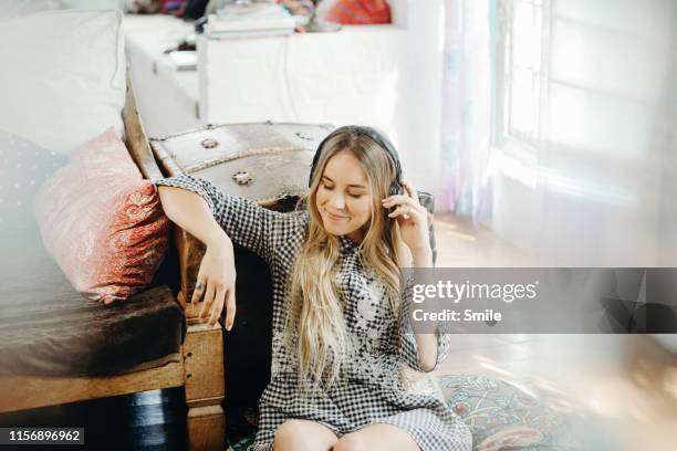 young woman sitting on the floor listening to music with headphones - personal stereo photos et images de collection