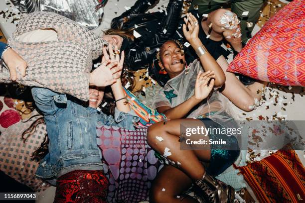 young friends having a pillow fight with confetti floating about - crazy party stockfoto's en -beelden