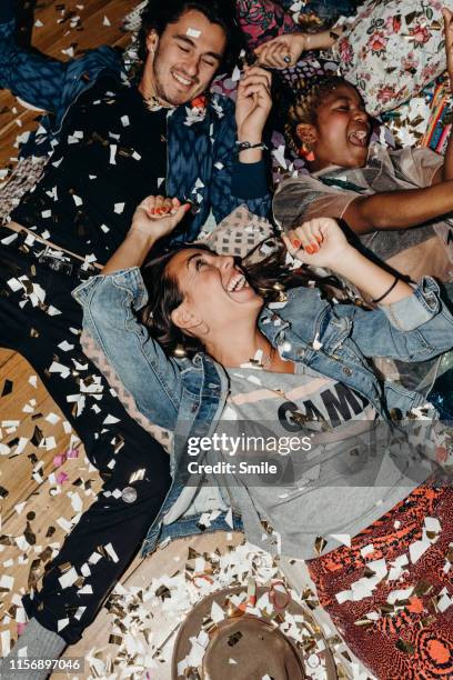 happy young friends on cushions and confetti on the floor - crazy party ストックフォトと画像