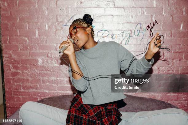 beautiful young woman singing with mic at home - personal stereo stockfoto's en -beelden