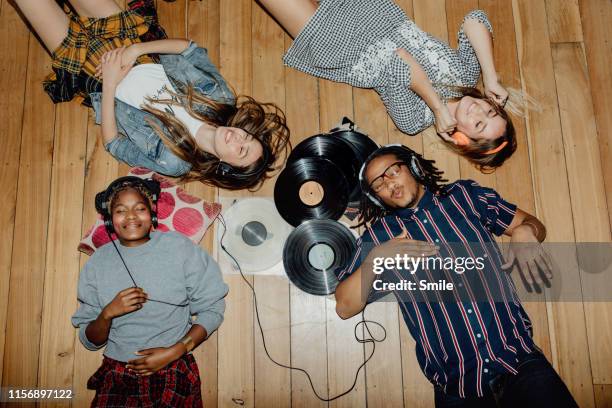 group of young friends listening to music with vinyls scattered about - happy smile stock-fotos und bilder