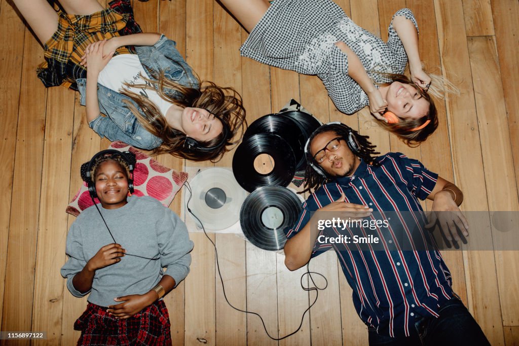 Group of young friends listening to music with vinyls scattered about