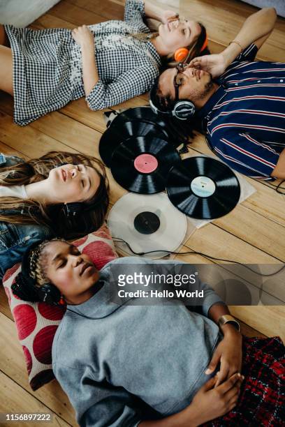 group of friends intently listening to vinyls whilst lounging on the floor - headphones turntable stock-fotos und bilder