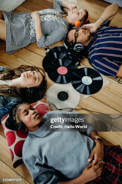 group of friends intently listening to vinyls whilst lounging on the floor - escape the room event stock pictures, royalty-free photos & images