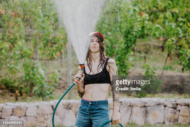 cool young woman defiantly spraying water in air - cape town water stock-fotos und bilder