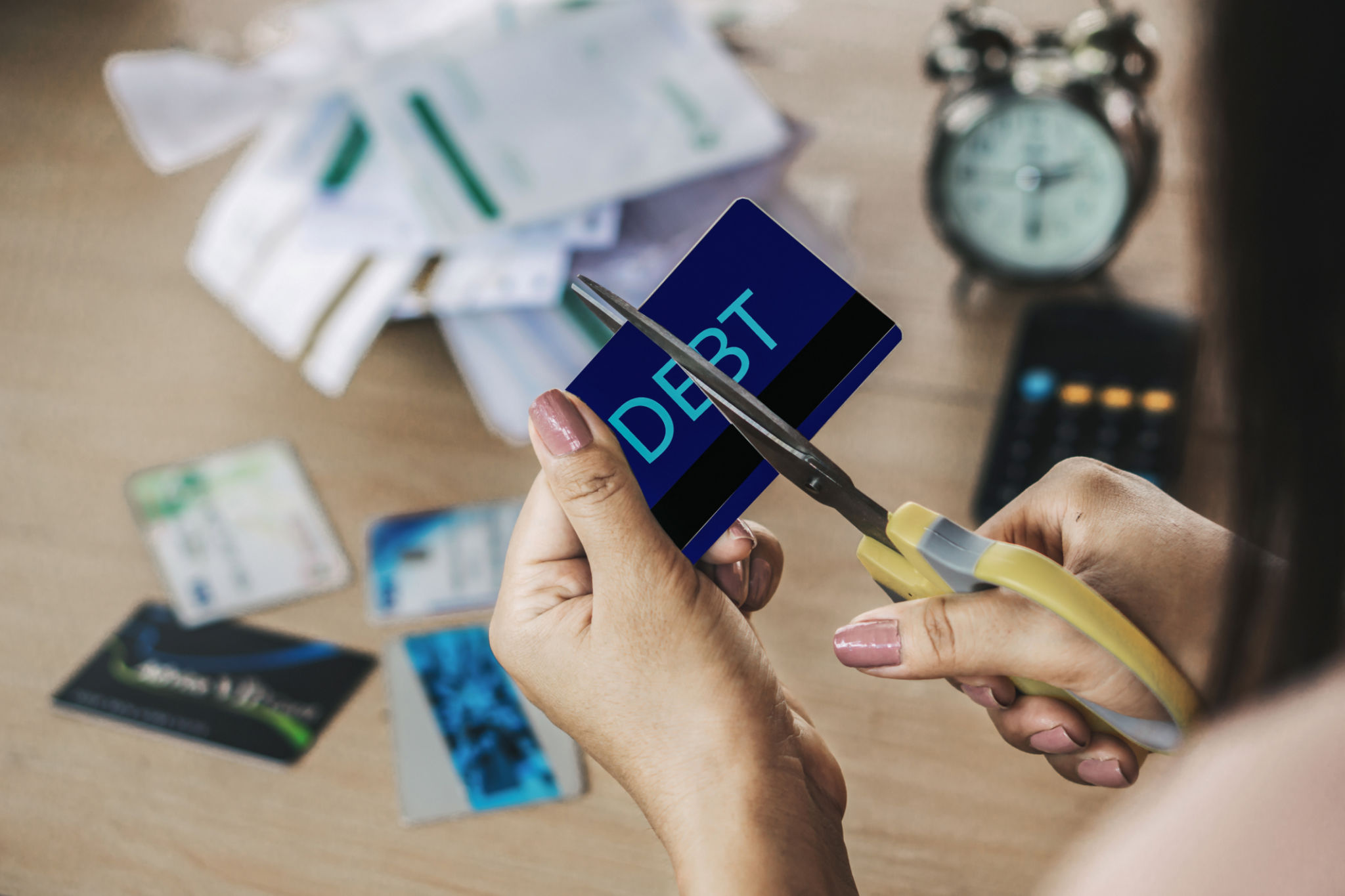 woman hand cutting credit cards by scissors with calculator and financial bills on desk woman hand cutting credit cards by scissors with calculator and financial bills on desk