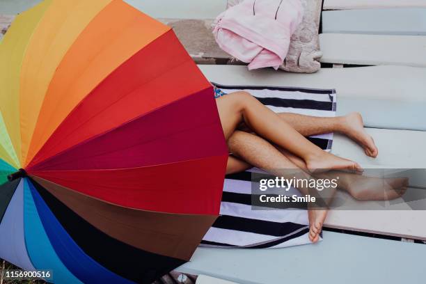 couples naked intertwined legs protruding from colourful umbrella - wamt stock pictures, royalty-free photos & images