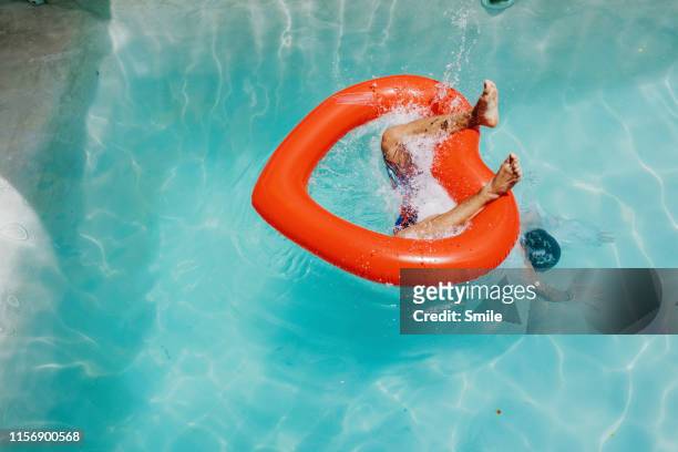 diving through heart-shaped inflatable into clear pool - euphorie stock-fotos und bilder