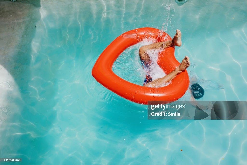 Diving through heart-shaped inflatable into clear pool