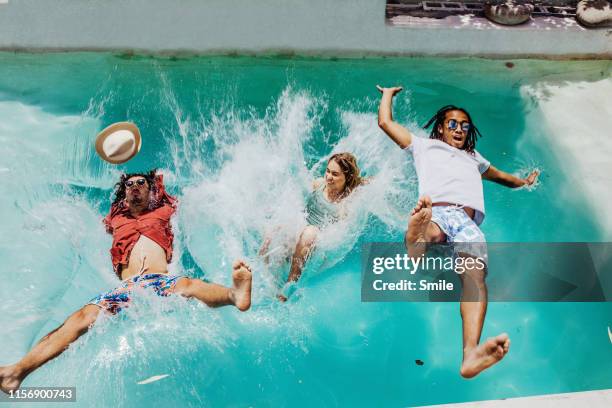 three friends falling backwards into swimming pool - den sprung wagen stock-fotos und bilder