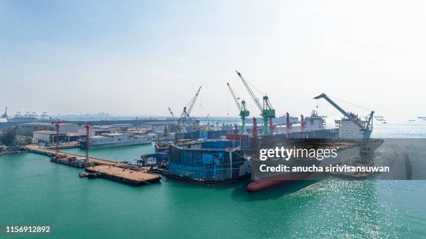 aerial view shipyard have crane machine and container ship in green sea . - marine engineering stockfoto's en -beelden