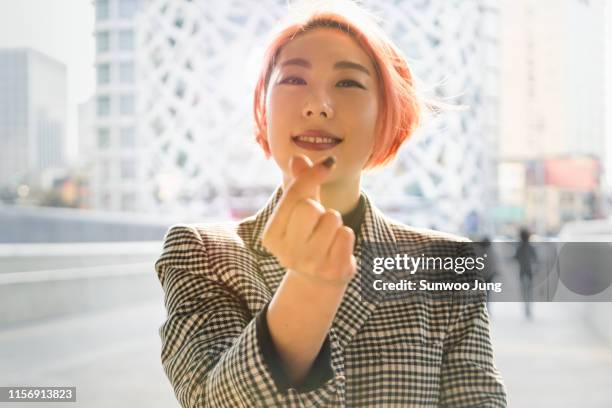 portrait of trendy woman expressing love with fingers - fashion sensation an evening of korean fashion and culture stock-fotos und bilder