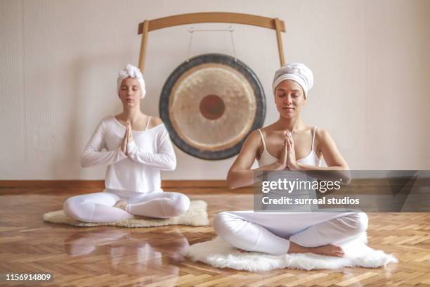 two beautiful females doing kundalini yoga - gong fotografías e imágenes de stock