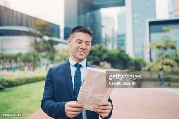 smiling entrepreneur reading a newspaper - center for asian american media stock pictures, royalty-free photos & images